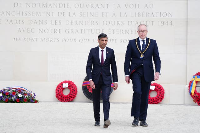 Rishi Sunak with the Royal British Legion chairman, Jason Coward, walking away from a war memorial in Normandy after laying wreaths