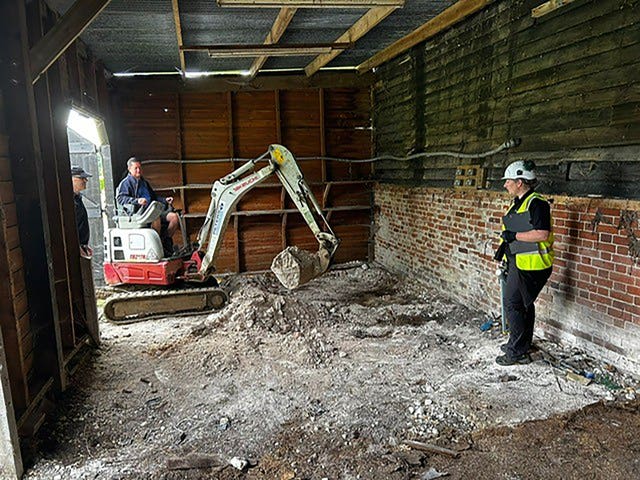 A small digger diggers up the earth in a barn