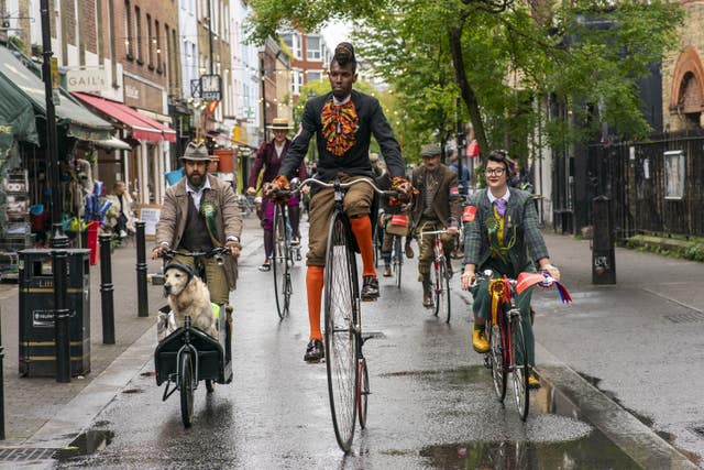 People dressed in tweed riding bikes, including a man on a penny farthing