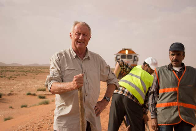 Chris Tarrant helps workers to clear sand off the tracks