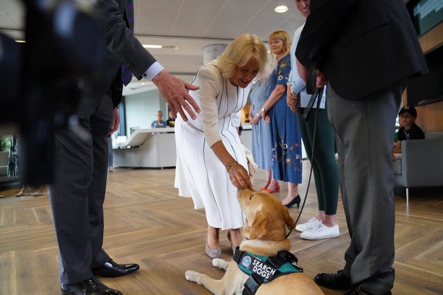 Queen Camilla meeting dog handler Mark Mills and his dog Flo as she arrives for her visit on day 10 of the 2023 Wimbledon Championships at the All England Lawn Tennis and Croquet Club in Wimbledon