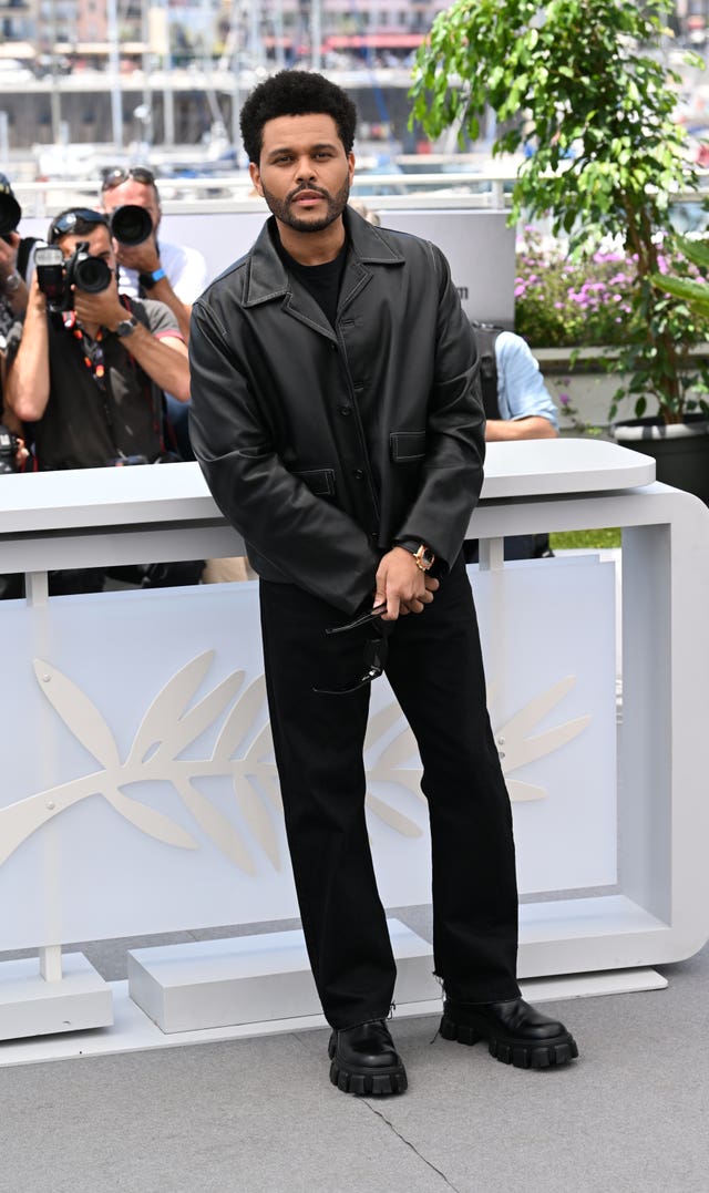 The Weeknd wearing black trousers and a black leather jacket posing for photos