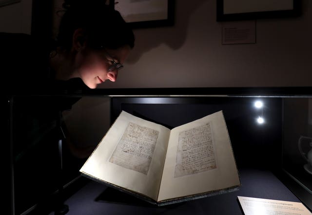 Sofie Davis, interpretation officer at Keats House, inspects Ode To A Nightingale as it goes on display at Keats House in London 