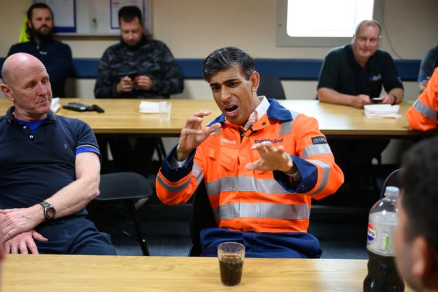 Rishi Sunak, dressed in a hi-vis Centrica jacket, reacts with mock horror on being presented with a glass of Pepsi 