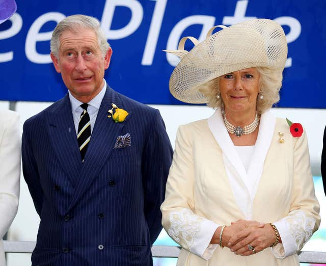 The Prince of Wales and the Duchess of Cornwall react to the sound of thunder as they attend the Melbourne Gold Cup Day at Flemington Race Course in 2012