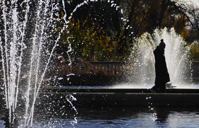 A bundled-up visitor walks between fountains in Hyde Park