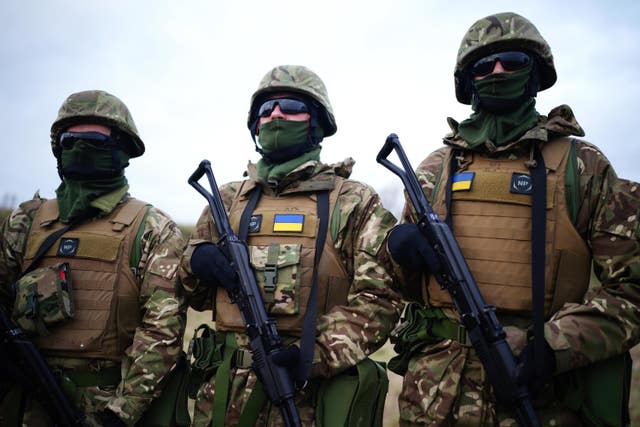 Three Ukrainian soldiers, their faces covered, pose for a photograph during a military exercise on Salisbury Plain