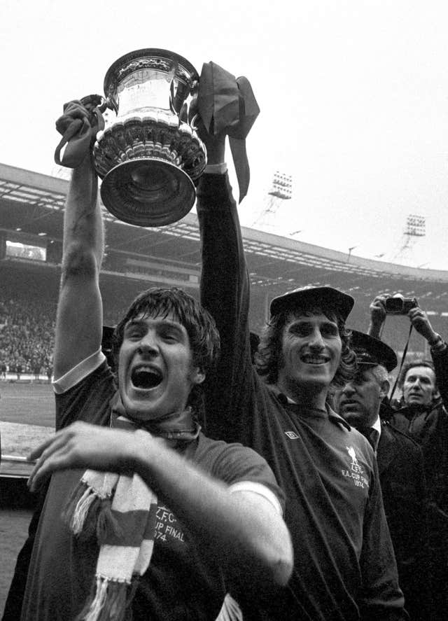 Liverpool captain Emlyn Hughes (left) and goalkeeper Ray Clemence joyously show off the FA Cup to the fans after a 3-0 victory over Newcastle