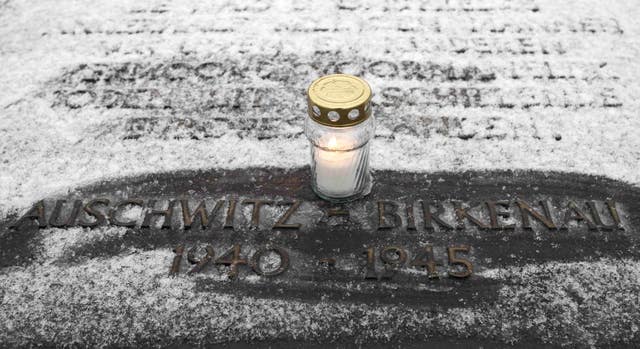A candle on a memorial plaque at the end of the railway tracks at Birkenau to mark International Holocaust Memorial Day  (Dave Thompson/PA)
