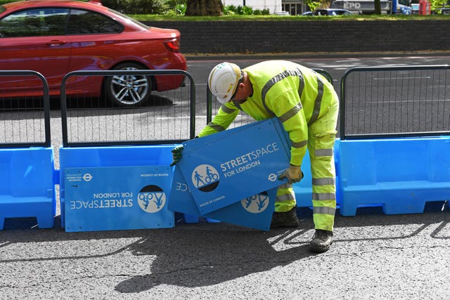 A worker puts the finishing touches to a pop-up cycle lane on Park Lane (Stefan Rousseau/PA)