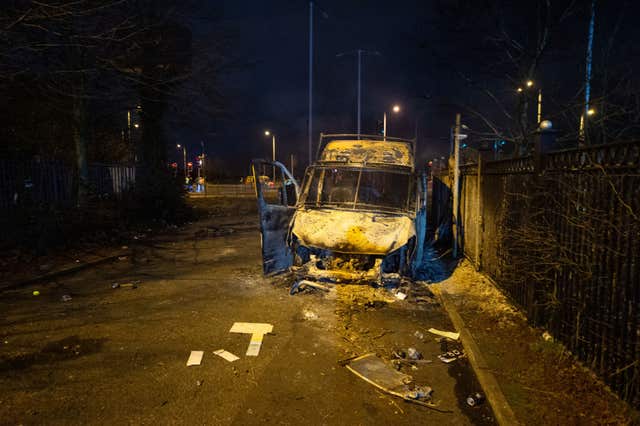 A burnt out police van after a demonstration outside the Suites Hotel in Knowsley, Merseyside.