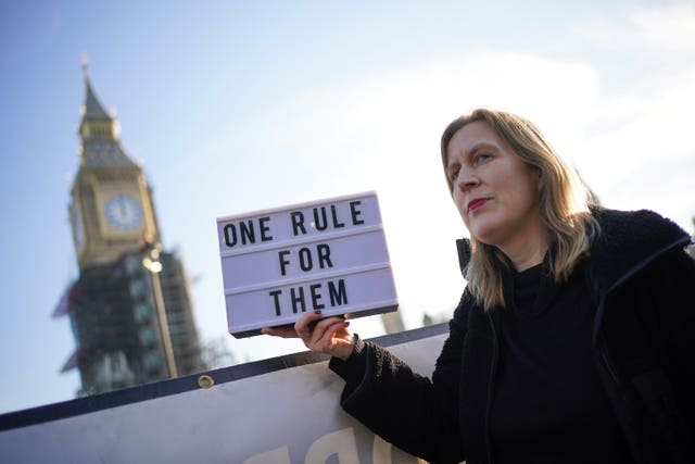 A protester outside Parliament with a sign saying 'one rule for them'