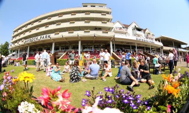 Racegoers enjoy the sun in front of the grandstand before the first race at Haydock Park Racecourse, Merseyside