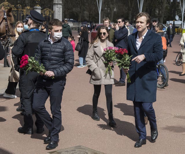 Member of the public carry flowers to leave at the gates of Buckingham Palace, London (Ian West/PA)