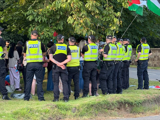 Police officers surround protesters, some holding Palestinian flags