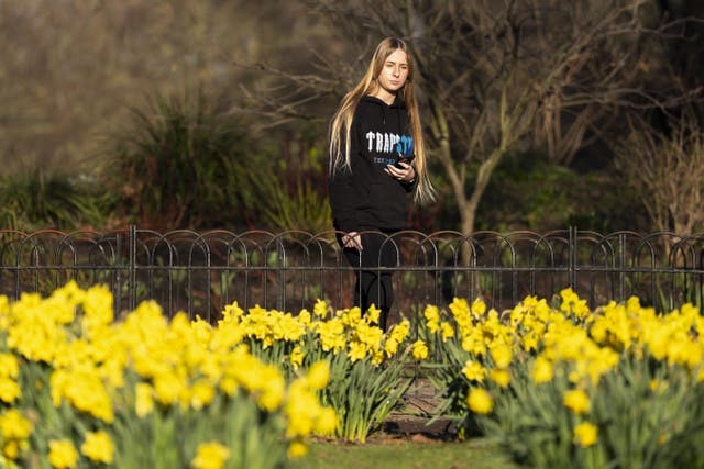 A young woman walking past daffodils growing in a park