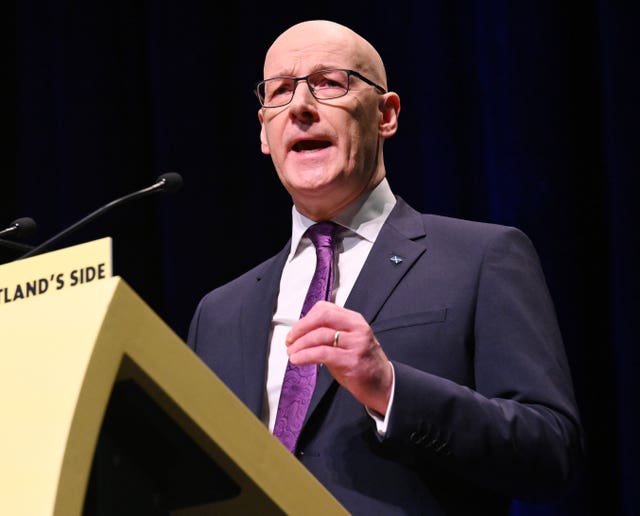 John Swinney speaking from an SNP lectern
