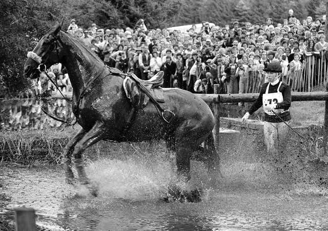  Anne stands in the water behind her horse after falling off at a jump