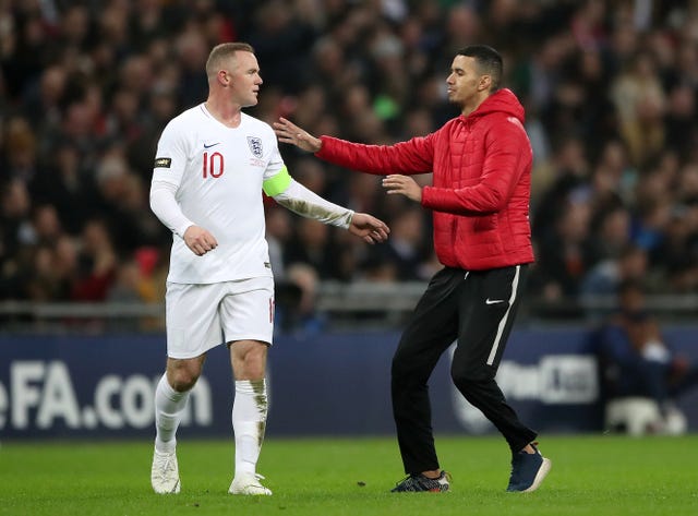 A pitch invader runs over to Rooney
