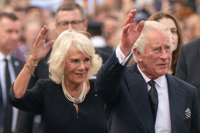 King Charles III and the Queen wave to the crowd outside Buckingham Palace