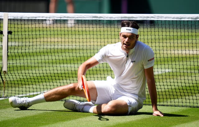 Taylor Fritz climbs off the floor near the net