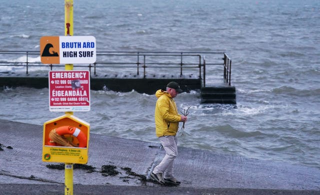 Person on the shoreline next to high tide warning signs