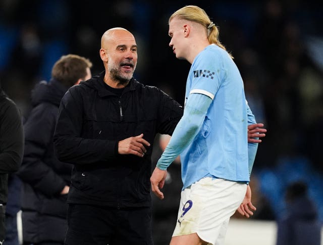 Pep Guardiola talks to Erling Haaland on the field