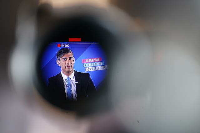 A tightly framed image of Rishi Sunak framed by the edge of a viewfinder on a TV camera during his speech with a Rec symbol above his head