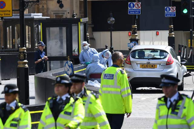 Forensic officers by the car that crashed into security barriers outside the Houses of Parliament 