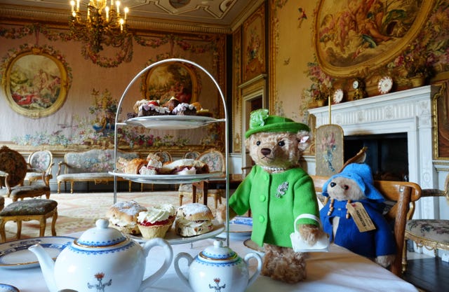 The Steiff bear, left, wearing a lime green coat with matching hat, pearl necklace and handbag, and a Paddington soft toy in his traditional blue coat and hat