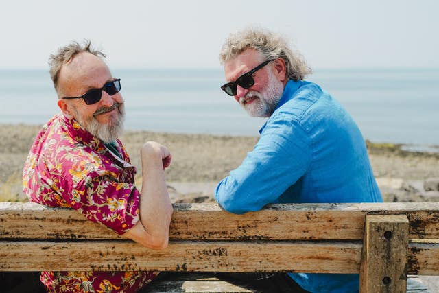 Si King and Dave Myers sitting on a bench next to a beach