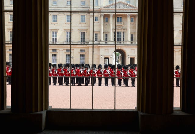 Foot Guards of the Household Division can be seen through a window as they line up at Buckingham Palace