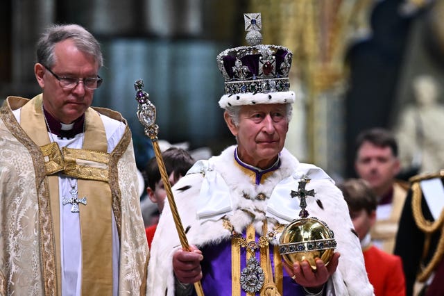 King Charles III wearing the Imperial state Crown carrying the Sovereign’s Orb and Sceptre leaves Westminster Abbey after the Coronation Ceremony on Saturday May 6, 2023