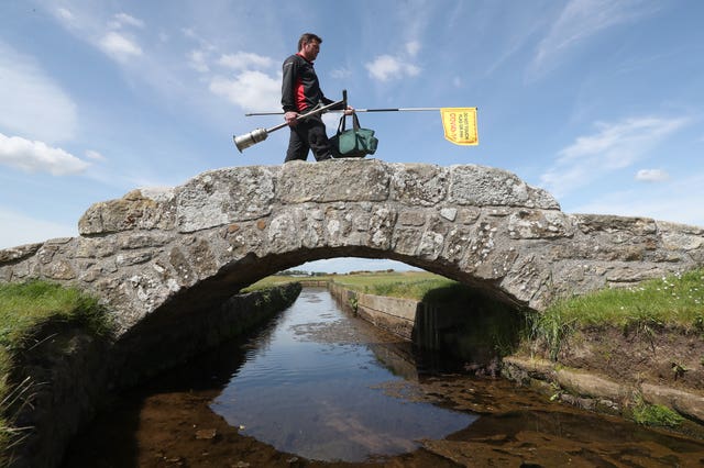 Greenkeeper Simon Connah crosses the Swilcan Bridge on the Old Course at St Andrews, in Fife