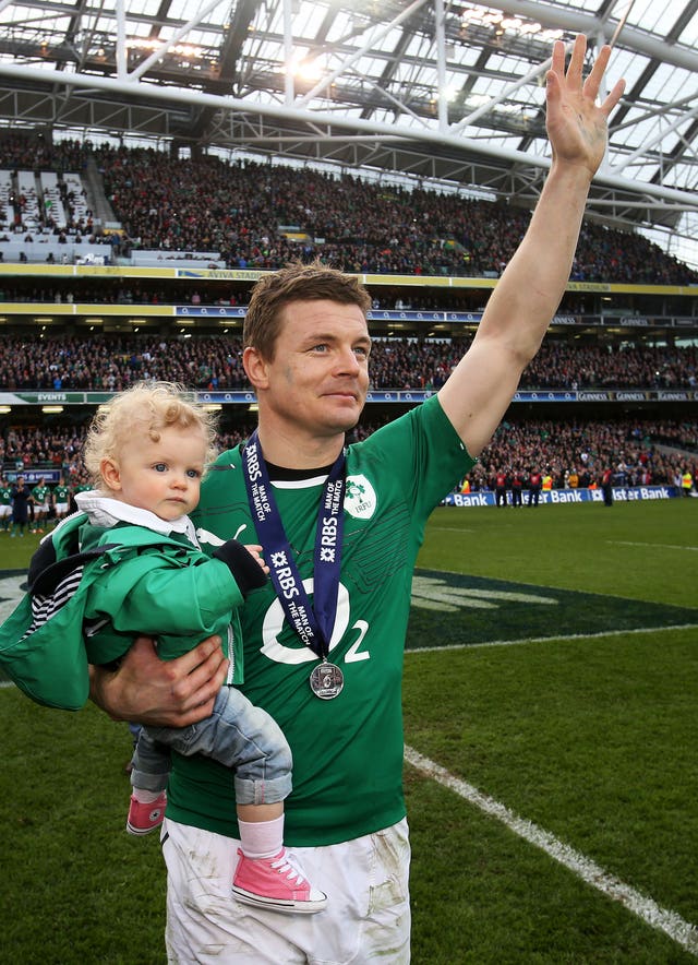 Brian O’Driscoll waves to the crowd carrying his daughter Sadie 