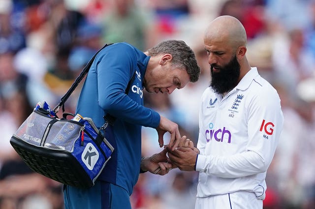 The England physio tends to Moeen Ali’s injured index finger