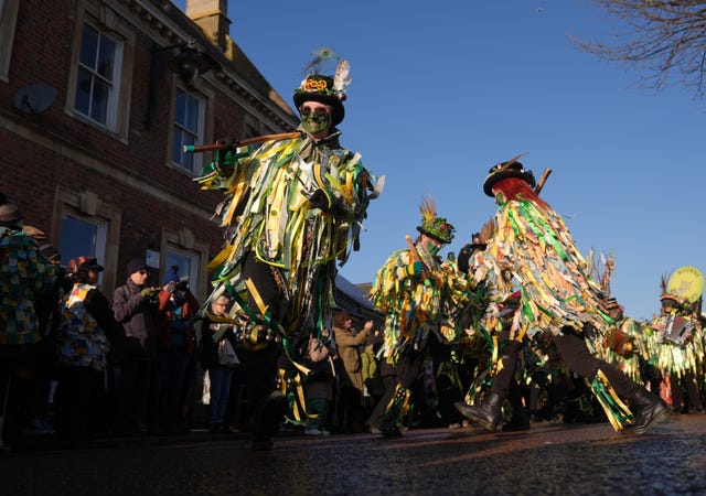 Morris dancers in bright green and yellow attire parading and dancing in the streets of Whittlesea