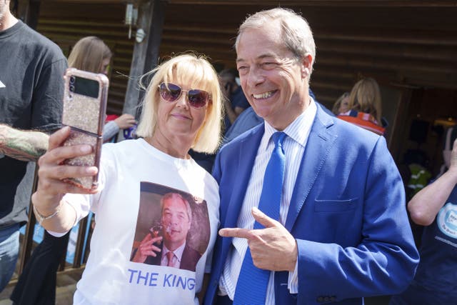 Nigel Farage poses for a selfie with a woman wearing a T-shirt with his picture on it and writing which says "The King" 