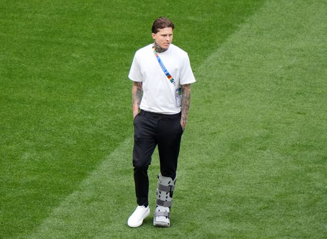 An injured Lydon Dykes walks on the pitch with his foot in a protective boot ahead of Scotland's match with Germany