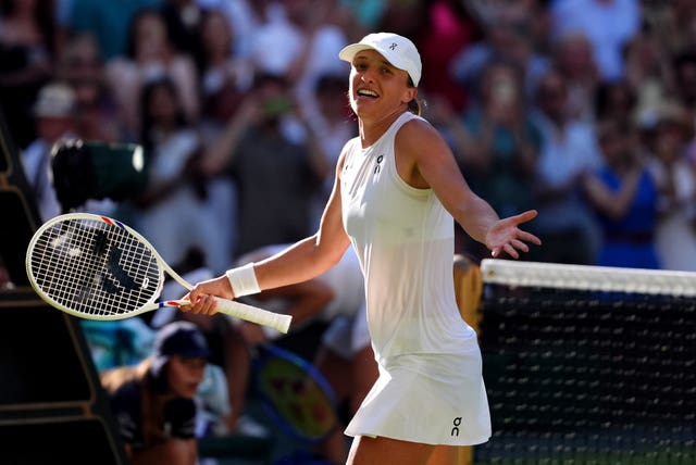Iga Swiatek holds her arms out after beating Belinda Bencic