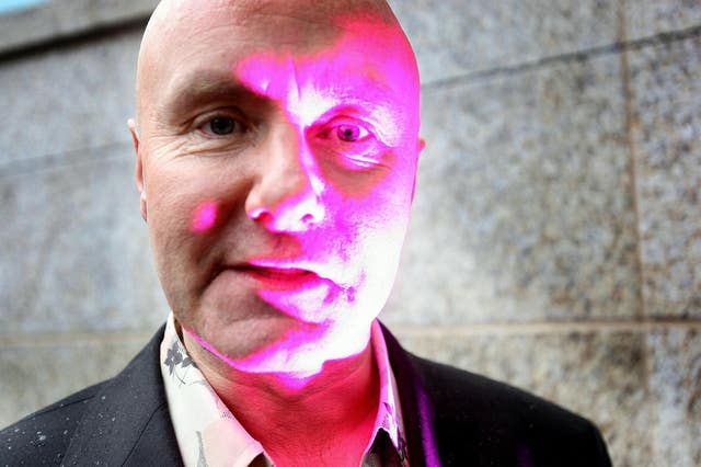 Headshot of Irvine Welsh, with a pink light shining over part of his face