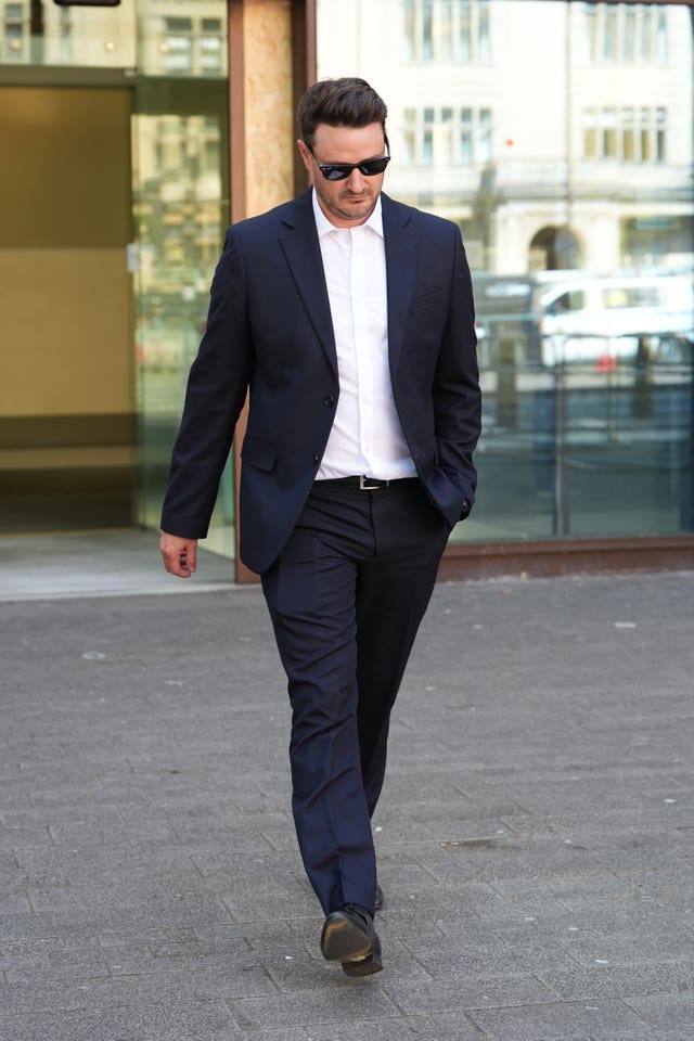 Joshua Williams walking outside, wearing suit and sunglasses
