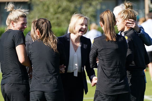 Prime Minister Liz Truss (centre) laughs during a visit to meet the England women’s football team