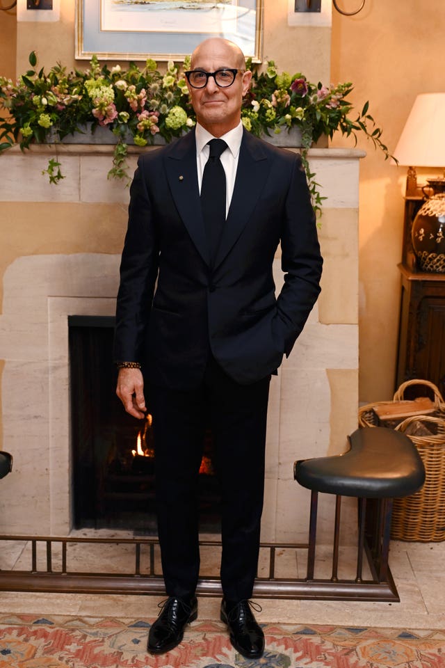 Hollywood star Stanley Tucci in a black tux by a fire