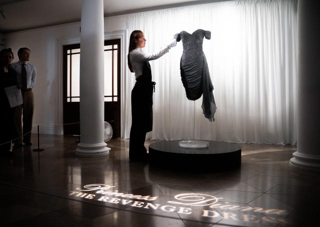 Auction house staff hold Diana, Princess of Wales's 'revenge dress' during a preview at Sotheby’s in central London of Diana, Princess of Wales’s black silk Christina Stambolian dress which was worn during a Vanity Fair fundraising dinner at the Serpentine Gallery in London in 1994, on the same night her then-husband the Prince of Wales publicly admitted his infidelity on national television