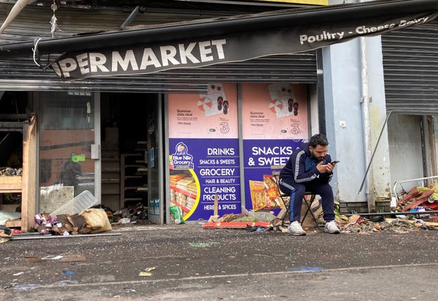 A man sits outside a destroyed supermarket