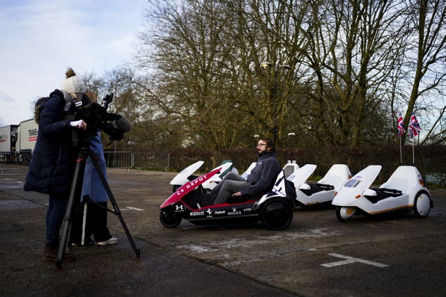 A journalist films a man on a Sinclair C5 vehicle