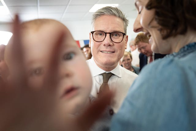 A baby tries to avoid the spotlight as Labour Party leader Sir Keir Starmer visits Worcester City Football Club