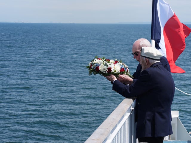 D-Day veterans Harry Birdsall, 98, and Alec Penstone (front), 98, throw a wreath into the sea from a ferry