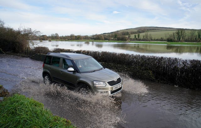 A car passes through flood water from the Cuckmere River in Alfriston, East Sussex 